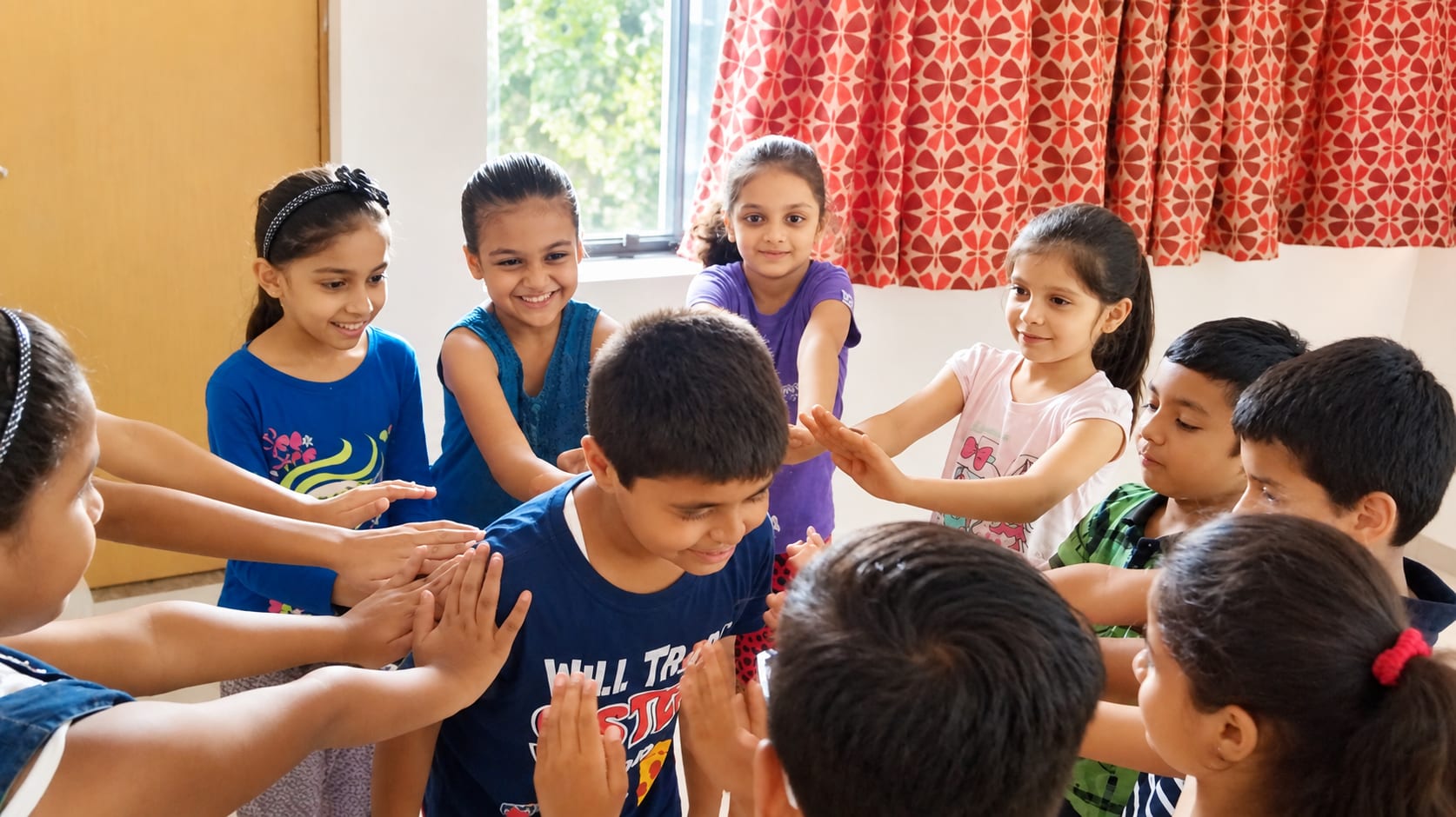 Children standing in a circle with their hands together during a group session at Jatan