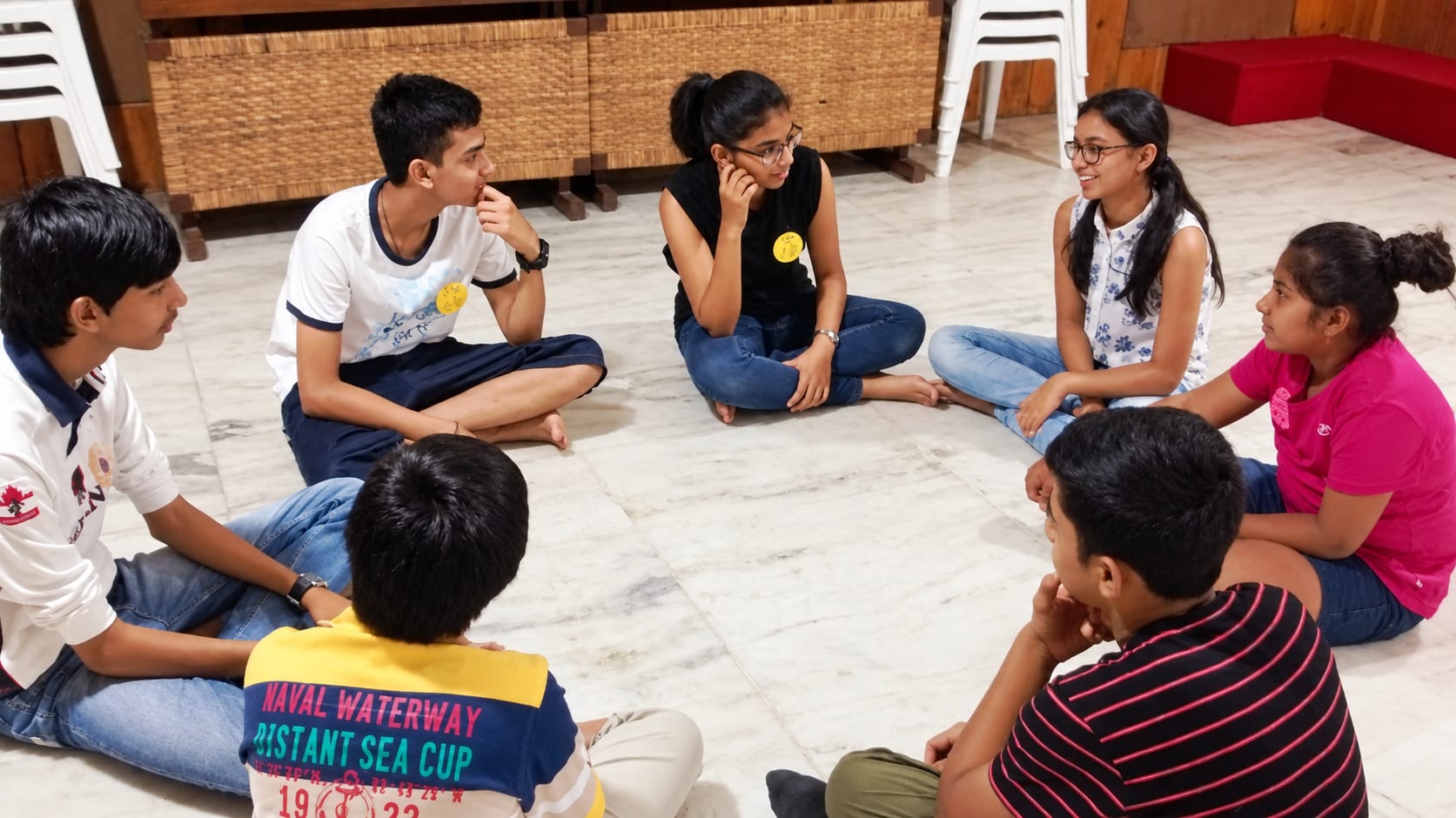 Teenagers sitting in a circle on the floor, talking during a group session at Jatan